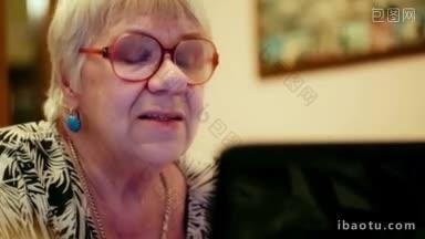 戴眼镜的情绪化的老年妇女用笔记本电脑视频聊天的特写镜头